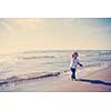 Adorable little girl having fun at beach during autumn day. Happy baby by the sea or ocean