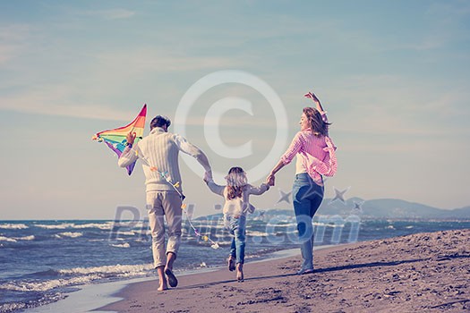 young family with kids resting and having fun with a kite at beach during autumn day