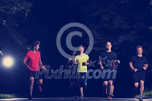 group of healthy people jogging in city park, runners team at night training