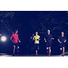 group of healthy people jogging in city park, runners team at night training