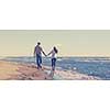 Young couple having fun walking and hugging on beach during autumn sunny day