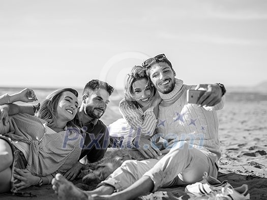 Group Of Young Friends Spending The Day On A Beach during autumn day Group Of Young Friends Spending The Day On A Beach during autumn day
