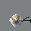 Close-up delicious dairy dessert cold white vanilla in a metal spoon for ice cream on a gray background. Summer concept. Space for text.