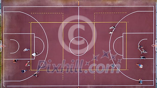 Aerial view strictly from above with the drone to a basketball court with players and ball. Sports game in basketball. Top view.