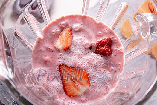 Mixed strawberries with yoghurt and chia seeds in a blender cup. Smoothie preparation process, top view