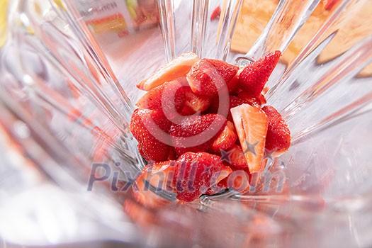 fresh ingredients for smoothies in electric blender, close up. Healthy eating, cooking and kitchen appliances concept. Top view