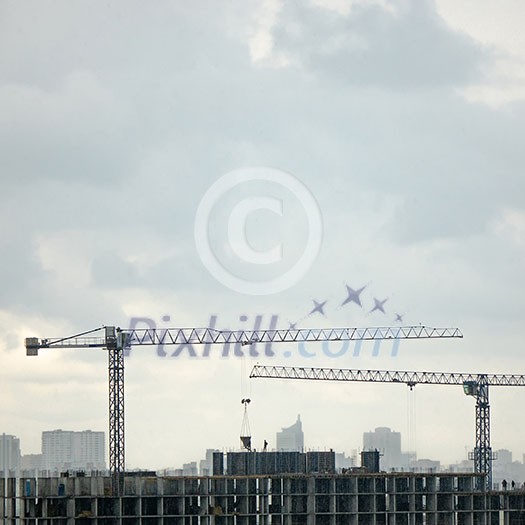 Panoramic photo from the drone of building under construction with two tower cranes against a gray cloudy sky. Panoramic photo from the drone of building under construction with two tower cranes against a gray cloudy sky.