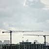 Panoramic photo from the drone of building under construction with two tower cranes against a gray cloudy sky.