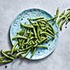 Pear sticks - organic green vegetables for preparing vegetarian salad on a blue plate on a gray table. Natural vegetarian detox dieting. Flat lay