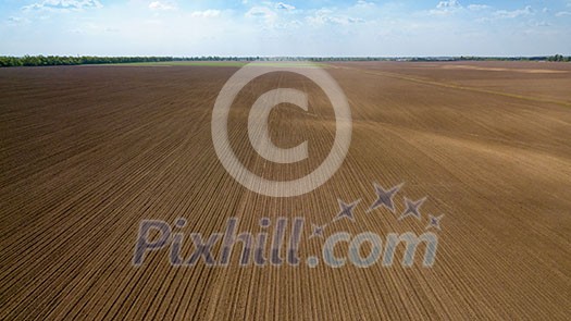 Agricultural landscape, plowed field in spring and forest in the distance against the blue sky, preparation of the earth for sowing works. Photo from the drone Agricultural landscape, plowed field in spring and forest in the distance against the blue sky, preparation of the earth for sowing works. Photo from the drone