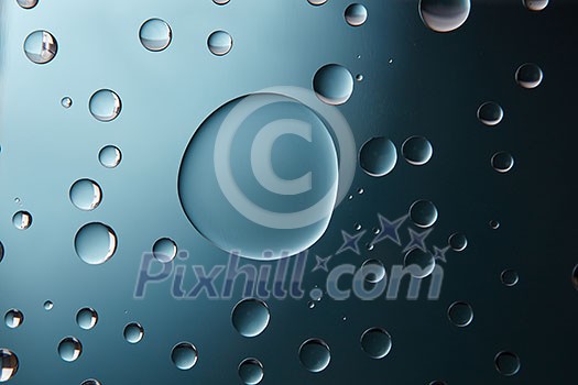 blue big and and small water drops on the glass blue gradient background