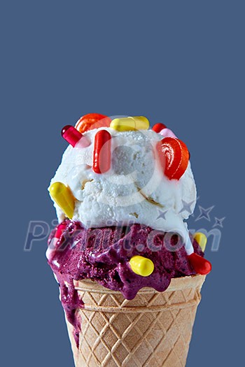 Close-up of waffle cone with a ball of berry and vanilla ice cream with red and yellow capsules and a lollipop against a blue background. The concept of summer catarrhal diseases and their treatment. Close-up of waffle cone with a ball of berry and vanilla ice cream with red and yellow capsules and a lollipop against a blue background. The concept of summer catarrhal diseases and their treatment.