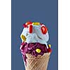 Close-up of waffle cone with a ball of berry and vanilla ice cream with red and yellow capsules and a lollipop against a blue background. The concept of summer catarrhal diseases and their treatment.