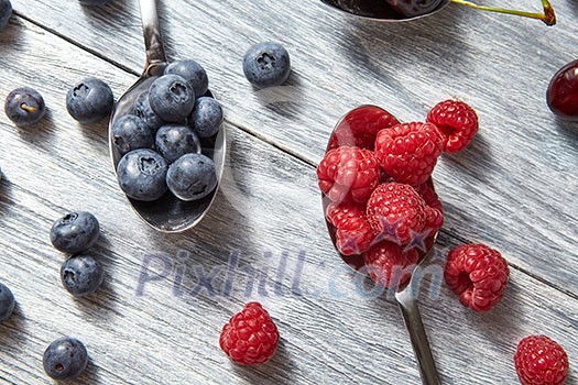 Delicious sweet berries on a spoon gray wooden background. Flat lay. Concept of vegetarian eating.