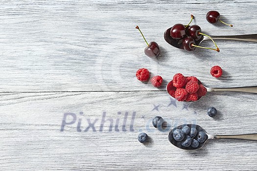Delicious sweet berries on a spoon on gray wooden background. Flat lay. Concept of healthy organic food with copy space. Flat lay. Delicious sweet berries on a spoon on gray wooden background. Flat lay. Concept of healthy organic food with copy space. Flat lay.