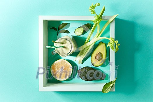 Healthy smoothie from green vegetables and fruits with flax seeds in a white bowl in square frame on a green background with copy space. Dietary organic food.