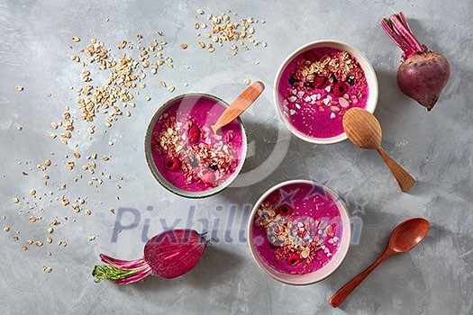 Superfoods red smoothie bowl with beetroot, oat flakes and raspberries on stone background, flat lay