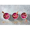 Beetroot smoothies with raspberries, granola, currants, almonds and sesame seeds in a plate with a wooden spoon on a gray concrete background with copy space. Healthy food. Top view
