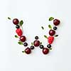 Letter W english alphabet in the form of a pattern of natural organic berries - ripe fresh raspberry, black currant, cherry, green mint leaf isolated on a white background. Top view.