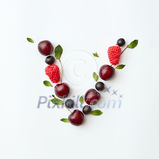 Letter V english alphabet in the form of a pattern of natural organic berries - ripe fresh raspberry, black currant, cherry, green mint leaf isolated on a white background. Top view.