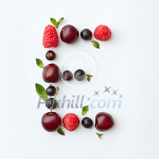 Letter E english alphabet in the form of a pattern of natural organic berries - ripe fresh raspberry, black currant, cherry, green mint leaf isolated on a white background. Top view.