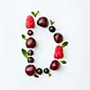 Letter D english alphabet in the form of a pattern of natural organic berries - ripe fresh raspberry, black currant, cherry, green mint leaf isolated on a white background. Top view.