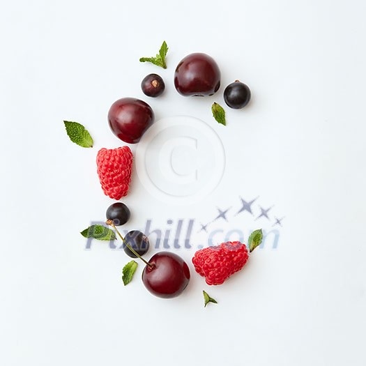 Letter C english alphabet in the form of a pattern of natural organic berries - ripe fresh raspberry, black currant, cherry, green mint leaf isolated on a white background. Top view.
