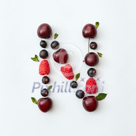 Letter N english alphabet in the form of a pattern of natural organic berries - ripe fresh raspberry, black currant, cherry, green mint leaf isolated on a white background. Flat lay
