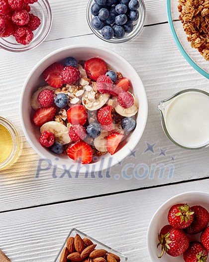Healthy organic breakfast from natural ingredienrs - granola, strawberries, blueberries, milk, almonds, floral honey. Concept of natural healthy detox food. Top view.