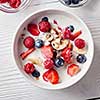 Close-up of a white ceramic bowl on a white table with natural organic ingredients for natural healthy breakfast. Concept of natural clean eating. Flat lay.