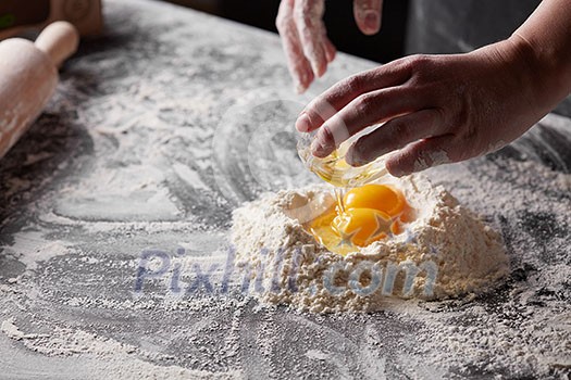 On a kitchen table a pile of flour with yolks, baker pours the squirrels into the flour. Step-by-step preparation of the dough On a kitchen table a pile of flour with yolks, baker pours the squirrels into the flour. Step-by-step preparation of the dough