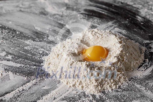 Flour and raw egg on the kitchen table, ingredients for kneading the dough Flour and raw egg on the kitchen table, ingredients for kneading the dough