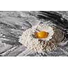 Flour and raw egg on the kitchen table, ingredients for kneading the dough