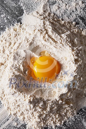 Top view heap of flour with raw egg on a kitchen table. Step-by-step cooking