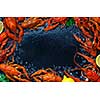 Fresh boiled crawfish with lemons and greens on a dark table with ice. Copyspace for text. Top view.
