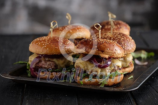 Homemade juicy burgers with beef, cheese and caramelized onions on the wooden table. Street food, fast food. Homemade juicy burgers with beef, cheese and caramelized onions on the wooden table. Street food, fast food.
