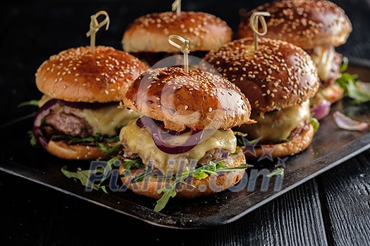 Homemade juicy burgers with beef, cheese and caramelized onions on the wooden table. Street food, fast food.