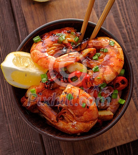 Large grilled BBQ shrimp with sweet chili sauce, green onion and lemon. Top view.