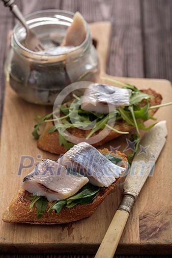 Herring sandwich (traditional Danish smorrebrod) on cutting board.