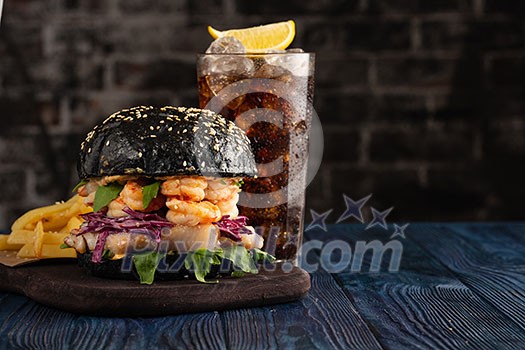 Black burger with fish and shrimps. Fishburger with prawns and French Fries.