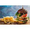 Large juicy burger with two cutlets and french fries on a wooden table