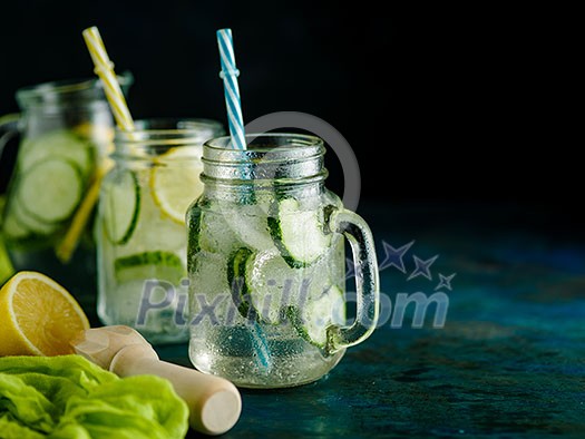 Fresh Summer Drink. Healthy detox fizzy water with lemon and cucumber in mason jar over dark background. Healthy food concept. Detox diet. Fresh Summer Drink. Healthy detox fizzy water with lemon and cucumber in mason jar over dark background. Healthy food concept. Detox diet.