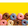 Variety of colorful tasty glazed donuts on a colored background.