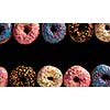 Variety of colorful tasty glazed donuts on a black background.