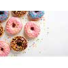 Variety of colorful tasty glazed donuts on a white background.