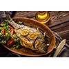 Grilled Dorado with lemon, thyme, rosemary and fresh salad on the wooden table