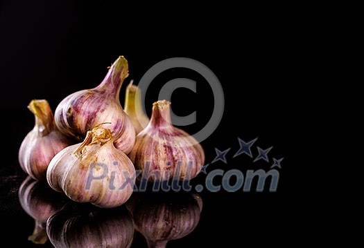 Fresh Garlic. Garlic bulbs on a black background. Place for text on the right. Copyspace. Fresh Garlic. Garlic bulbs on a black background. Place for text on the right. Copyspace.
