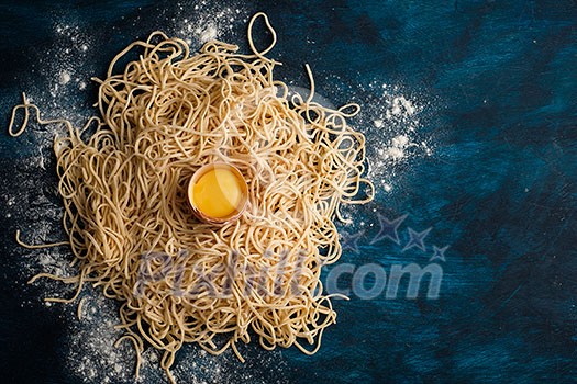 Dried egg noodles. Raw Fresh Spaghetti on blue wooden background.