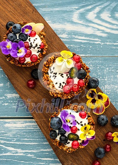 Dessert with sunflower seeds, yogurt and fresh berries on blue wooden table