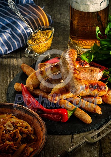 Grilled sausages and stewed cabbage with a mug of beer on a wooden table. Rustic style. Snacks for the Oktoberfest. Grilled sausages and stewed cabbage with a mug of beer on a wooden table. Rustic style. Snacks for the Oktoberfest.